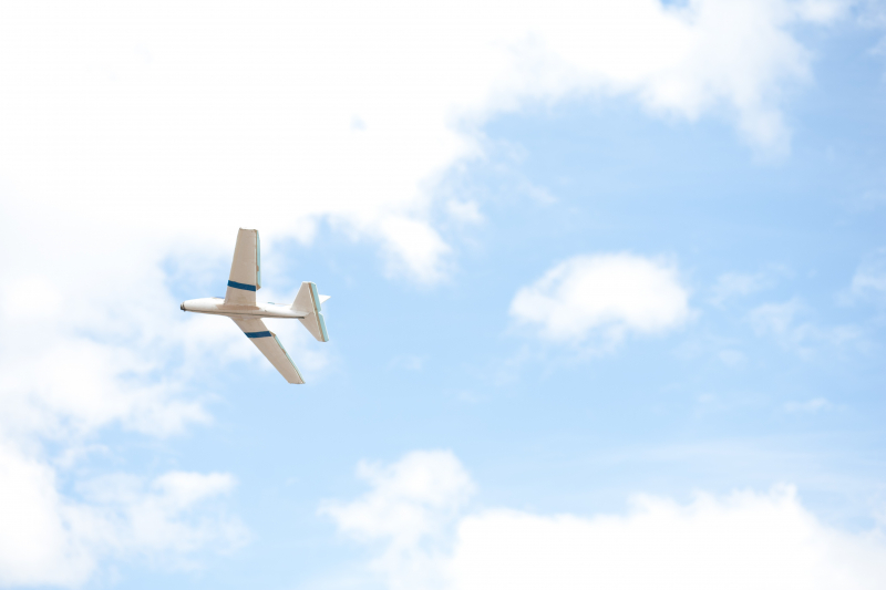Modellflygplan mot blå himmel med lite vita molntussar.