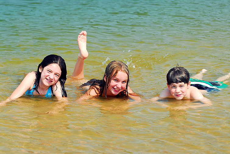 Två flickor och en pojke som badar.