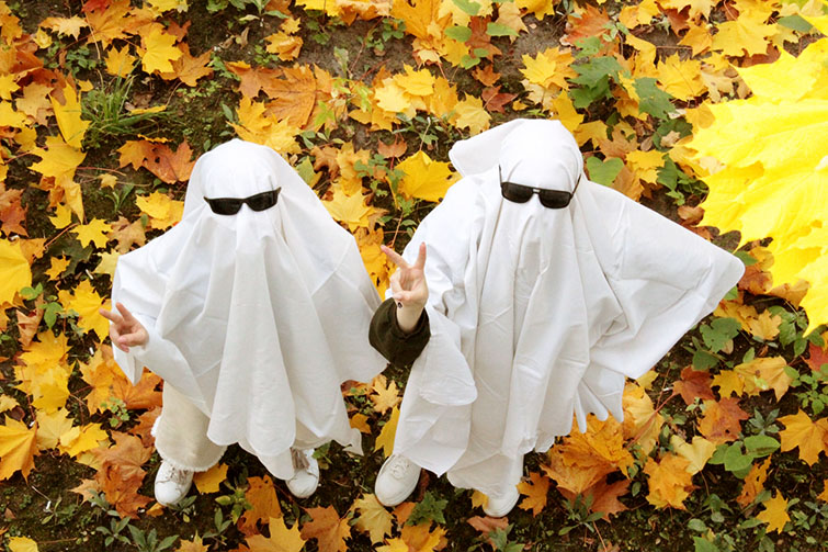 Två yngre personer utklädda till spöken med solglasögon.